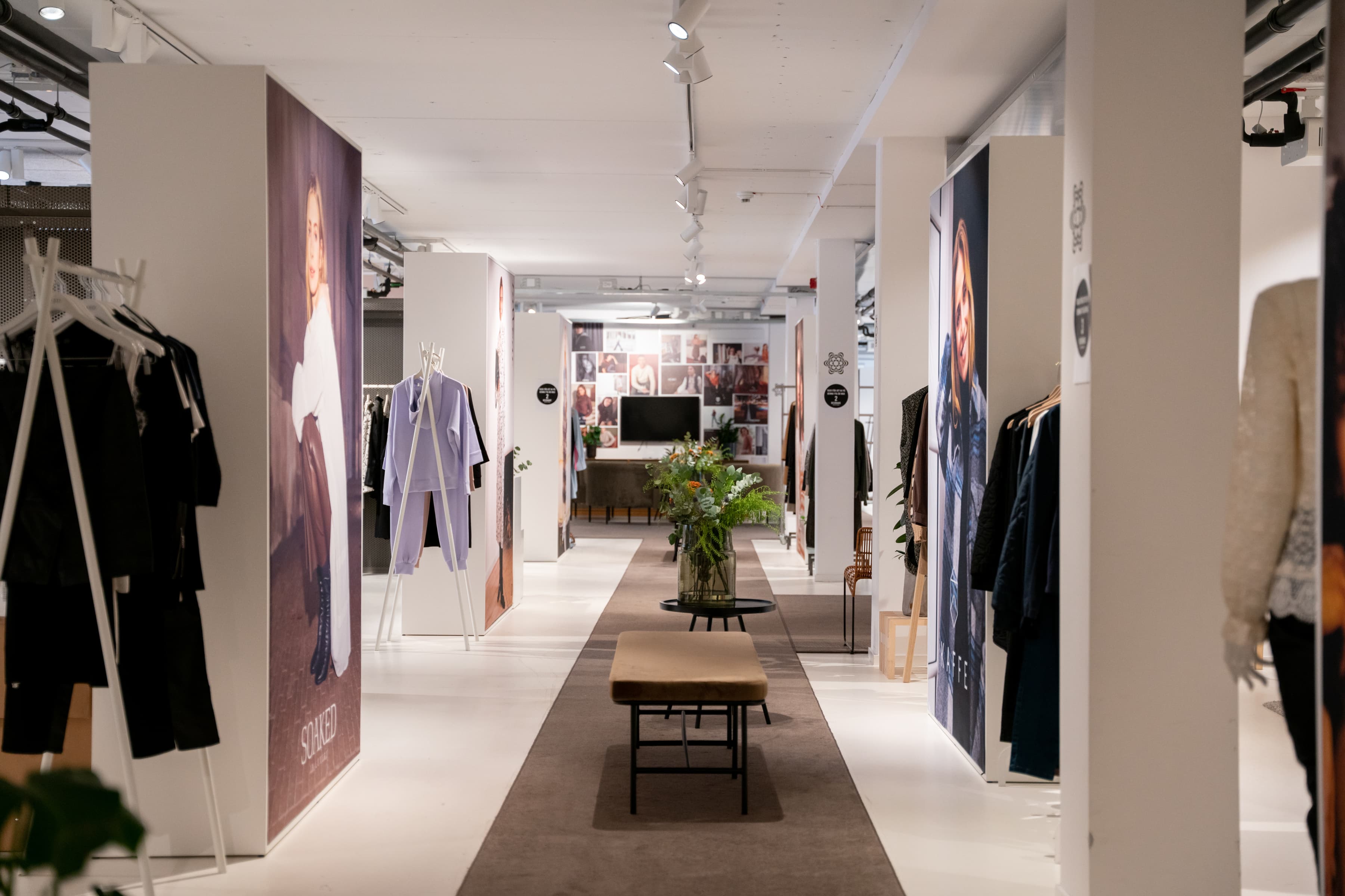 Ett showroom med kläder utställda och en bänk mitt i rummet.