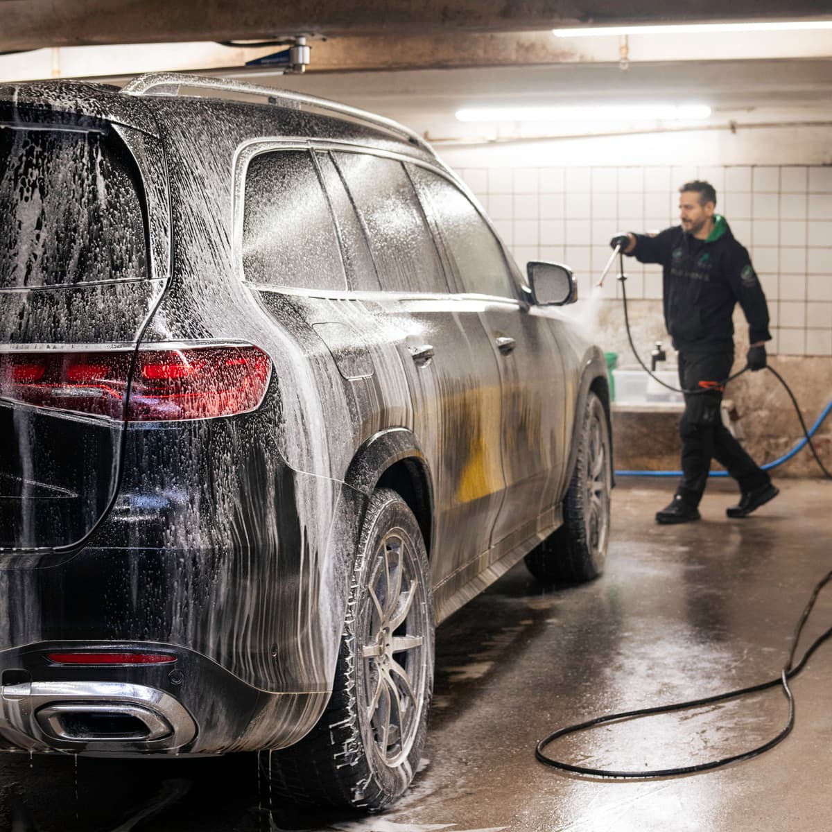 En man som tvättar en bil i ett garage.