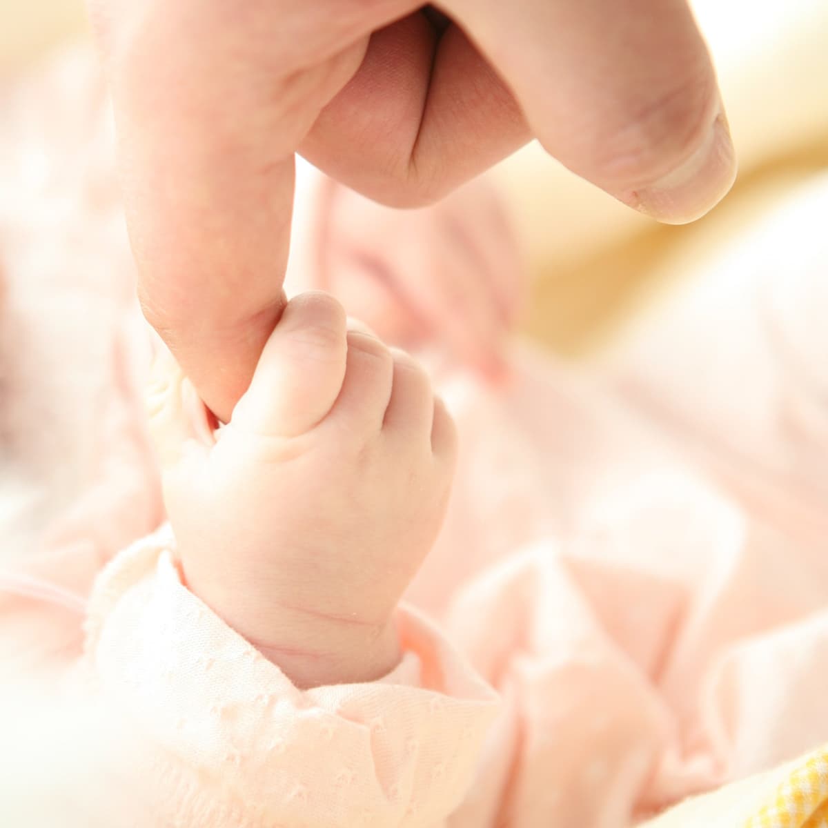 En person som håller en babys hand i luften.