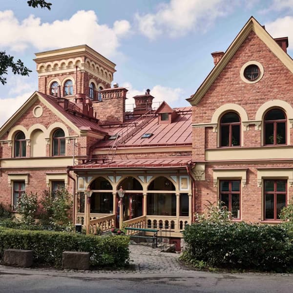 Ett stort hus i rött tegel med ett vackert tegeltorn.